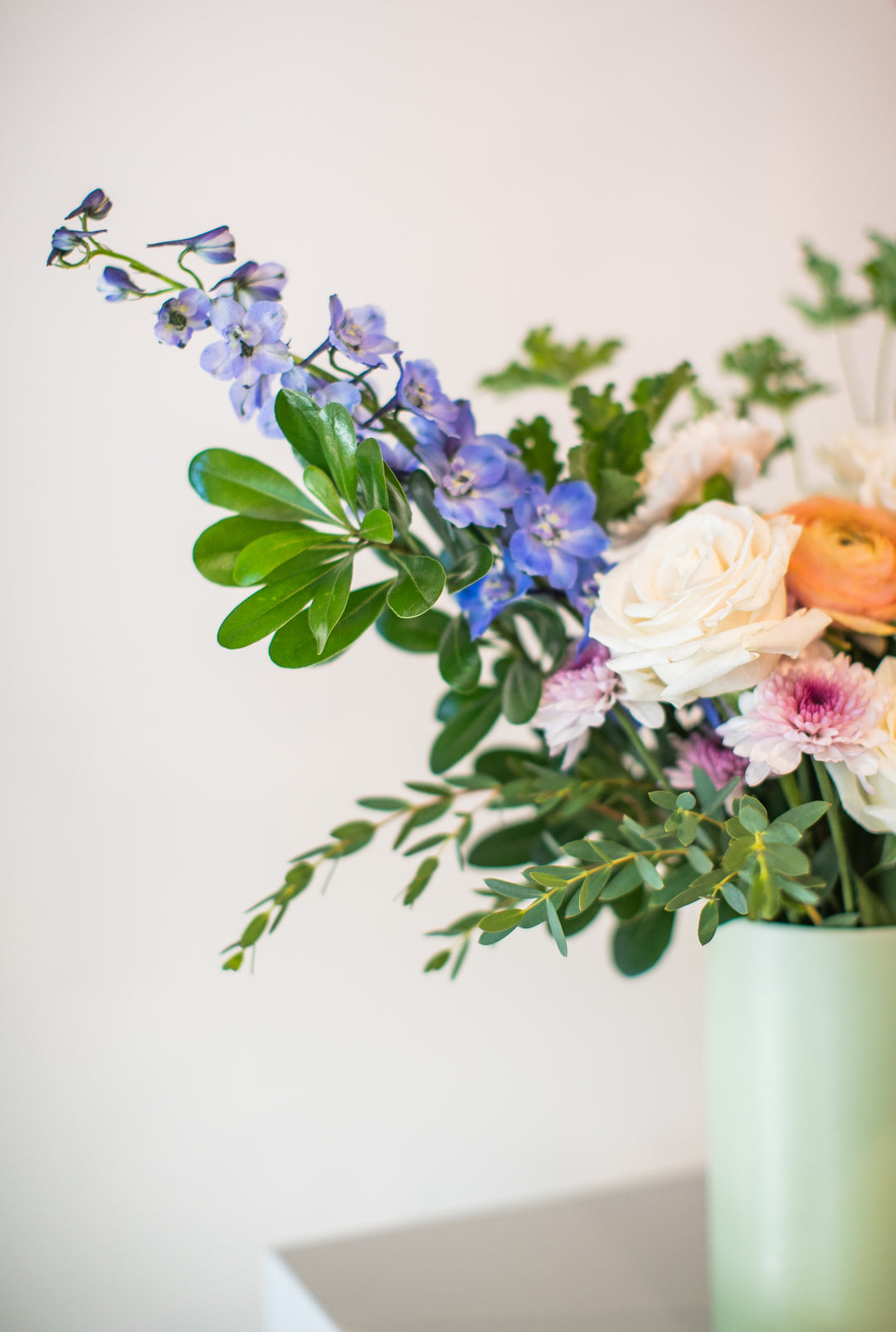 Floral arrangement in a green vase on a white surface