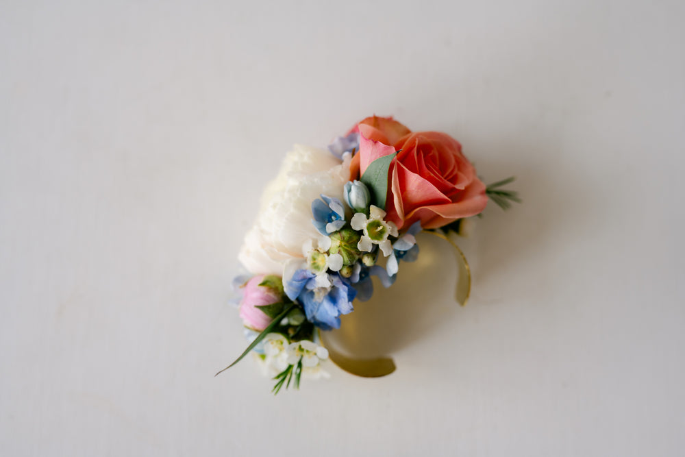 Soft pinks, whites, blue wrist corsage on gold cuff