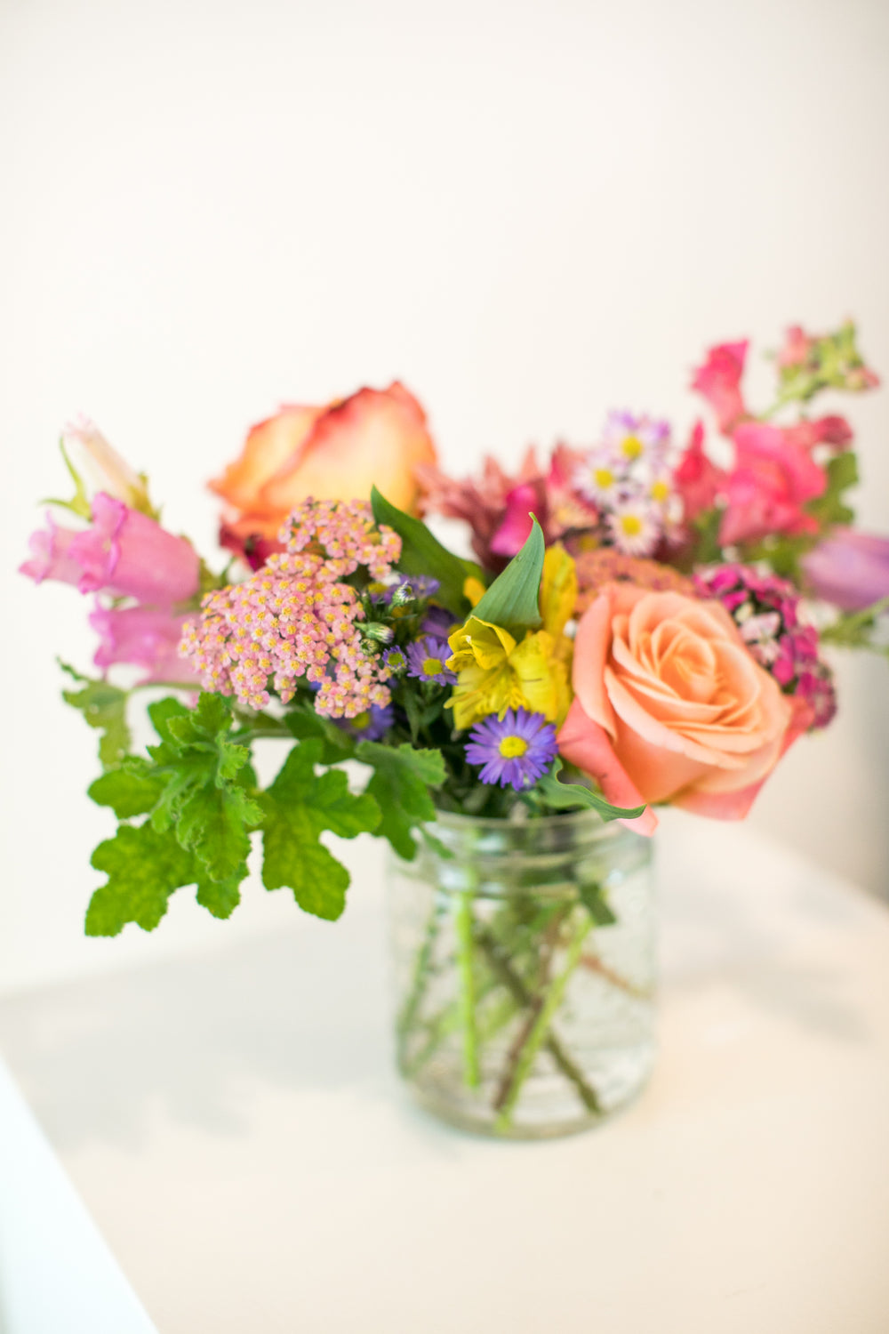 Short glass vase of colorful flowers arranged in Kansas City