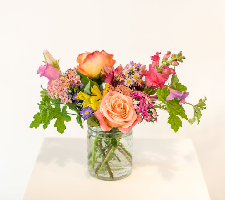 Short glass vase of colorful flowers arranged in Kansas City